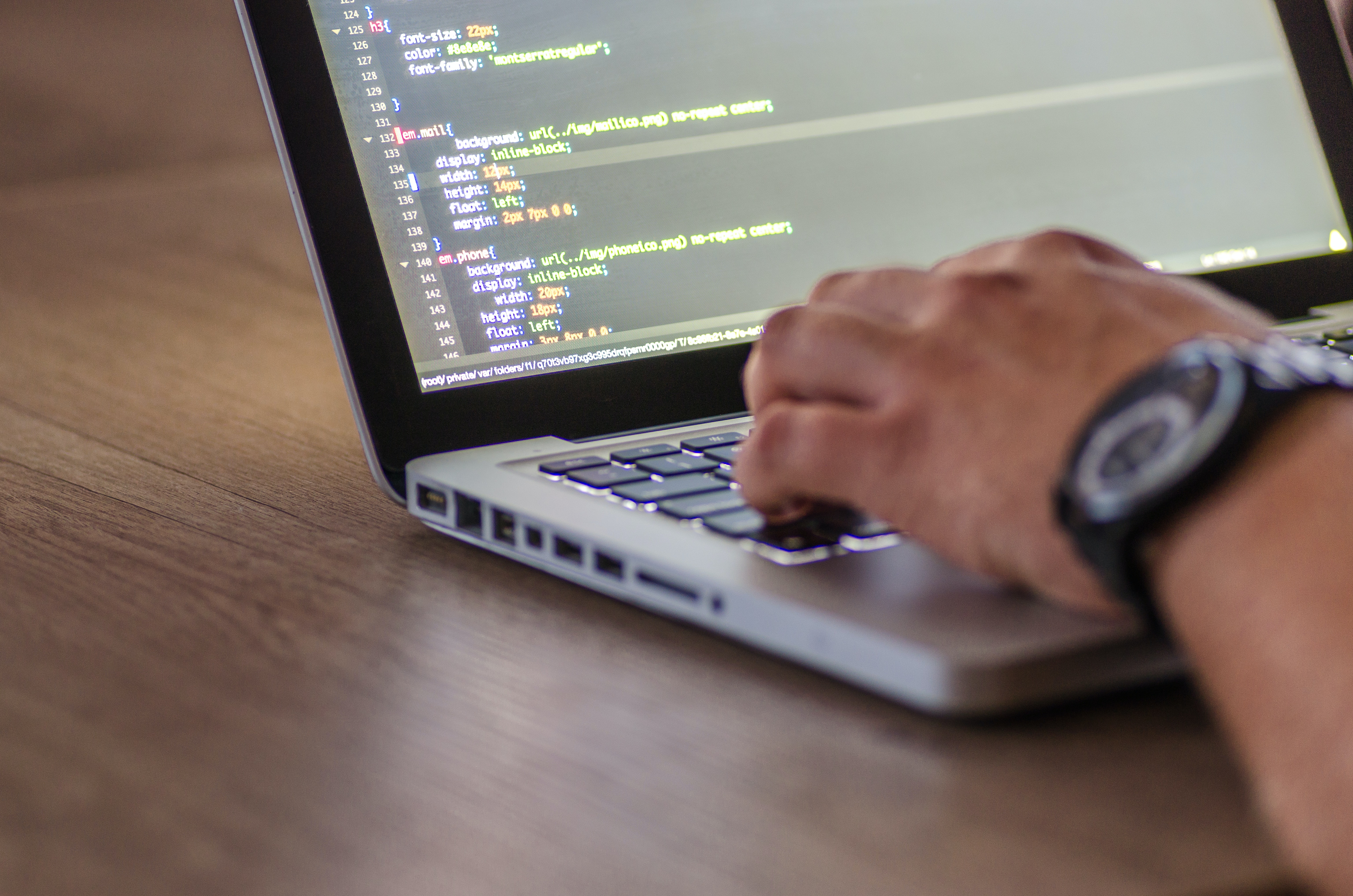 man hand typing coding on a grey laptop 