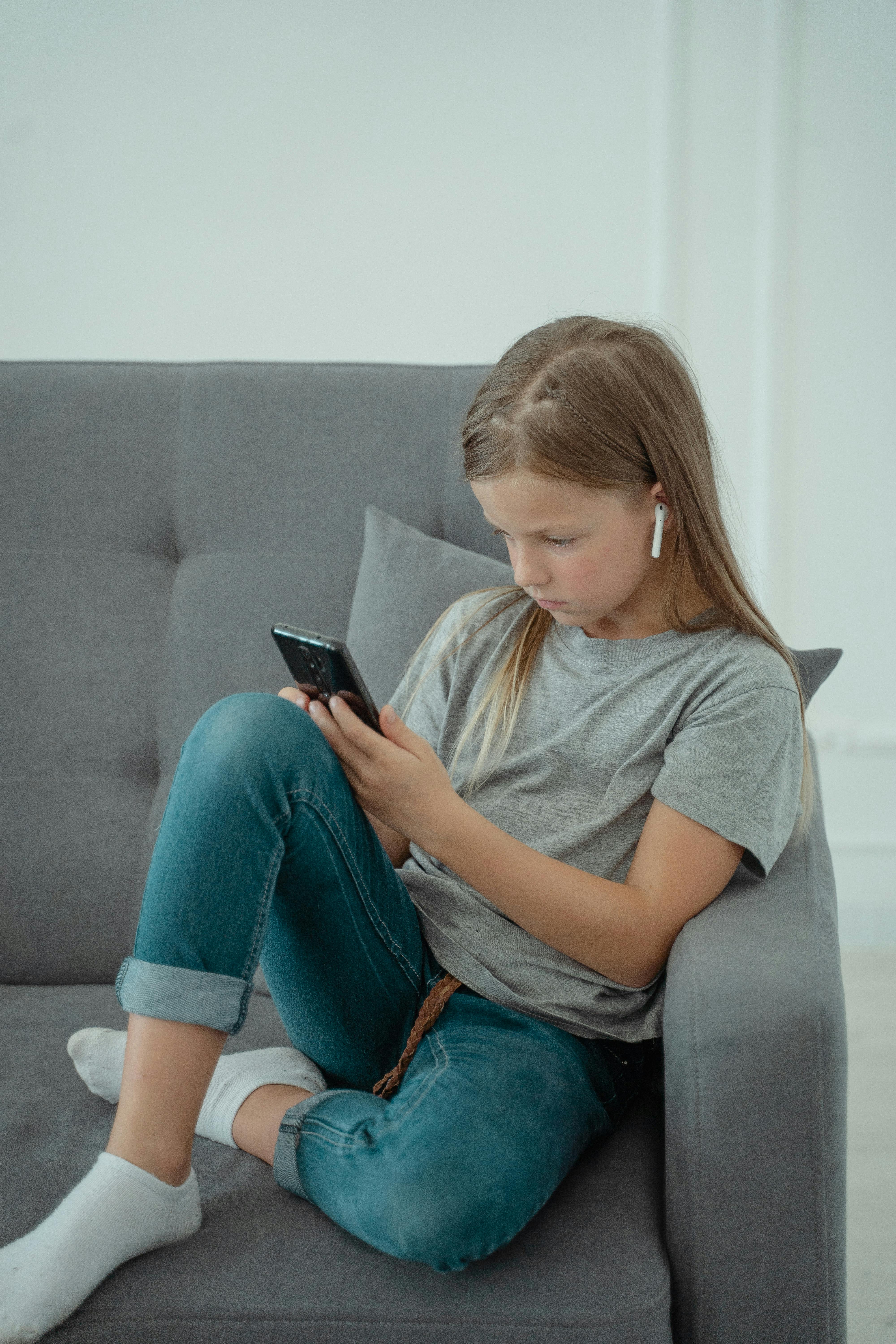 girl with a phone with educational app on a sofa 