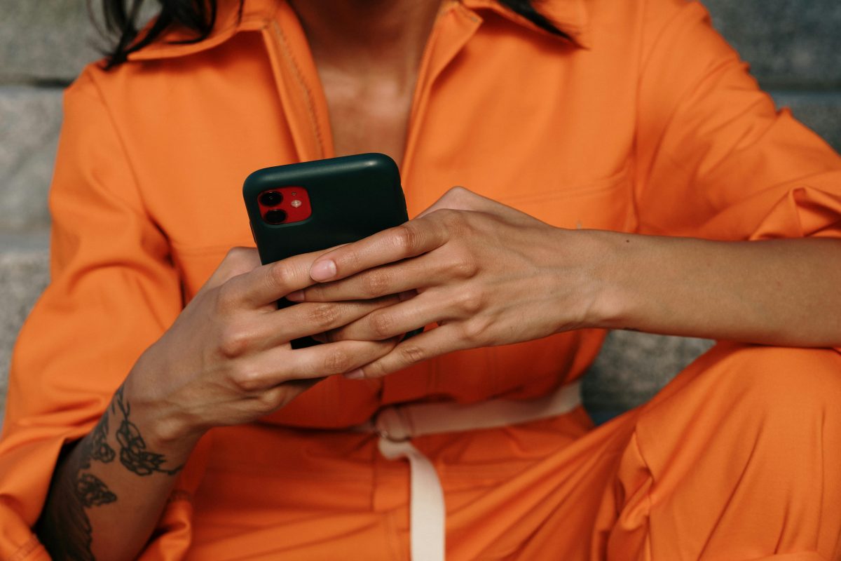 woman in orange one piece with phone