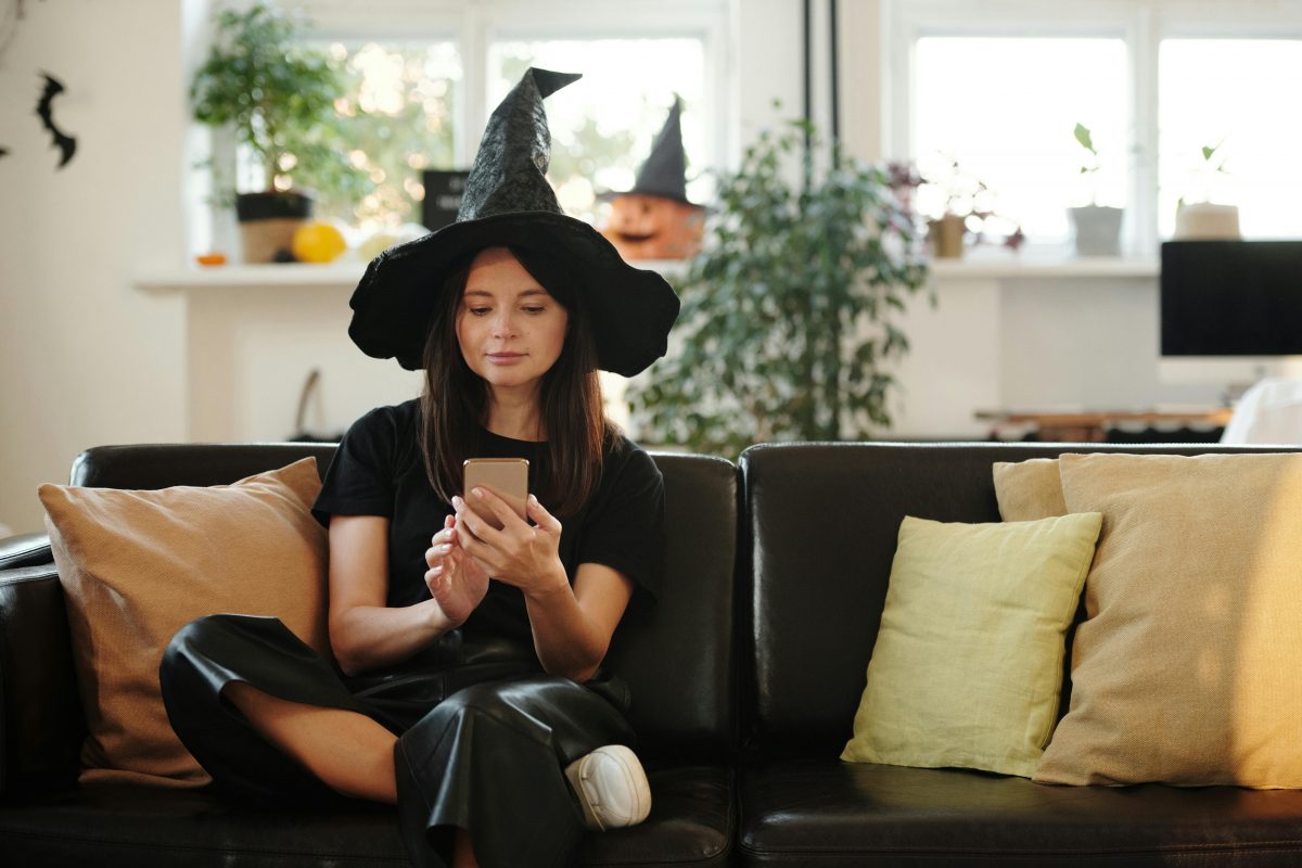 halloween witch with a phone on a sofa