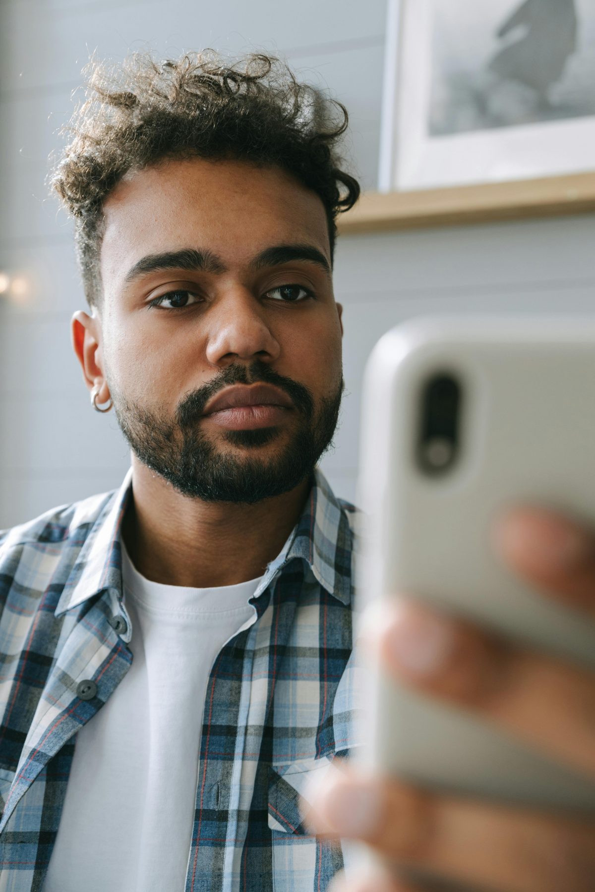 guy in plaid shirt with phone looking at phone