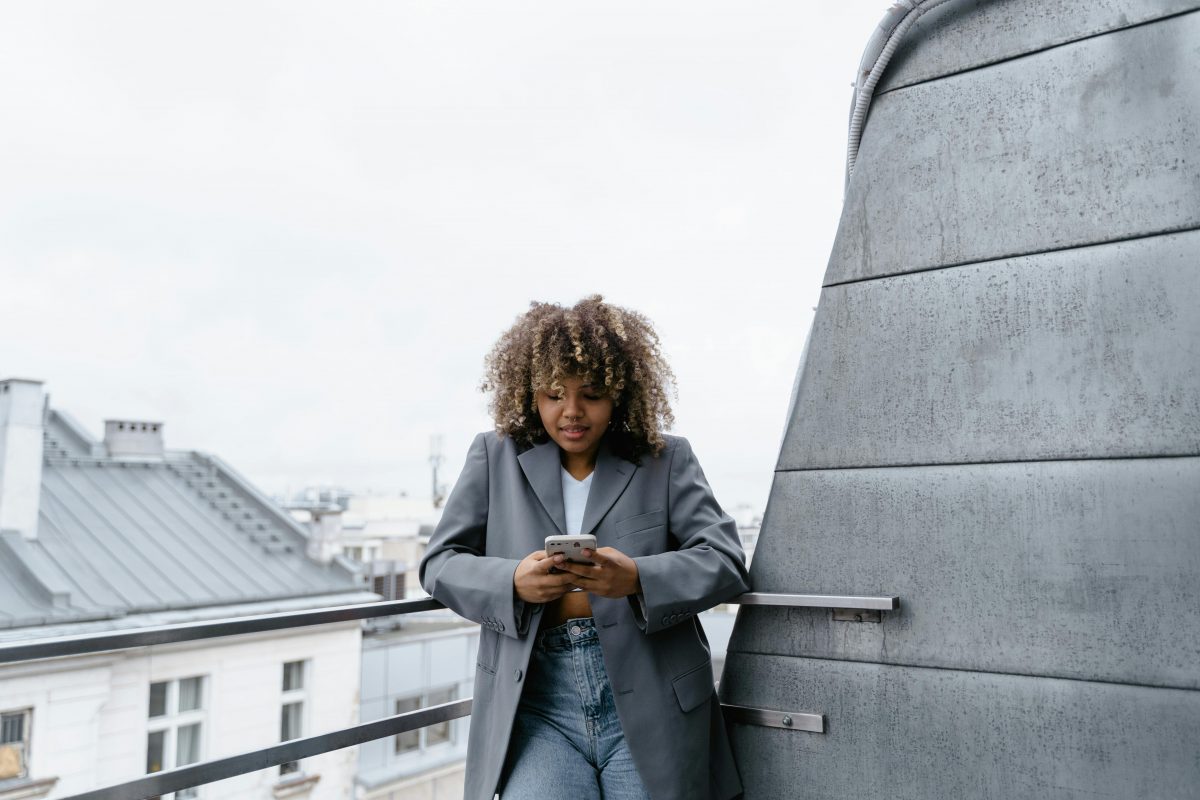 black woman with afro on rooftop looking at phone